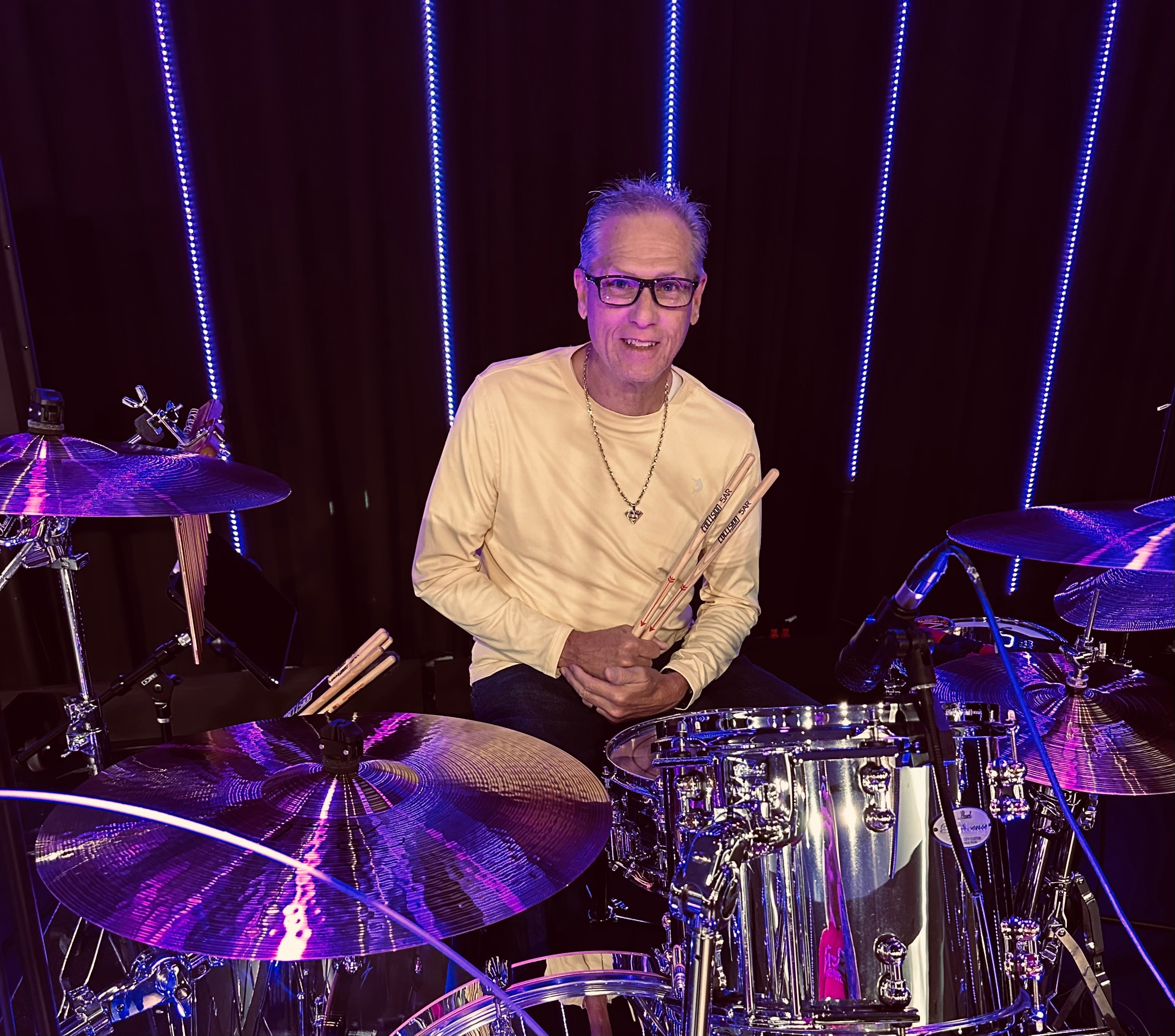Drummer performing on stage with neon lights