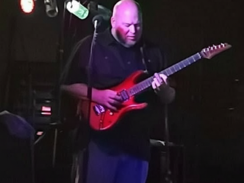 Guitarist playing red electric guitar on stage